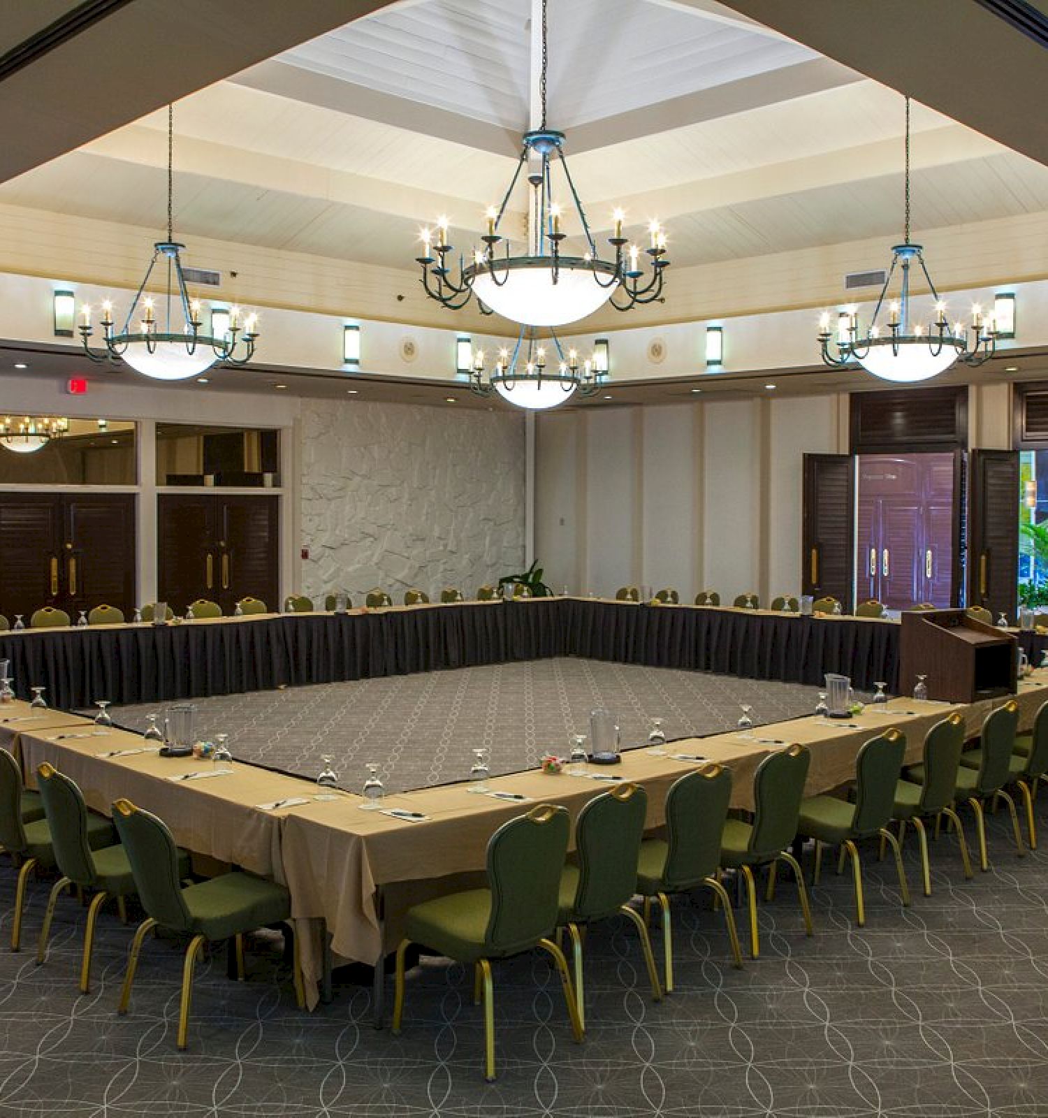 Conference room with a large U-shaped table setup, chairs, and chandeliers.