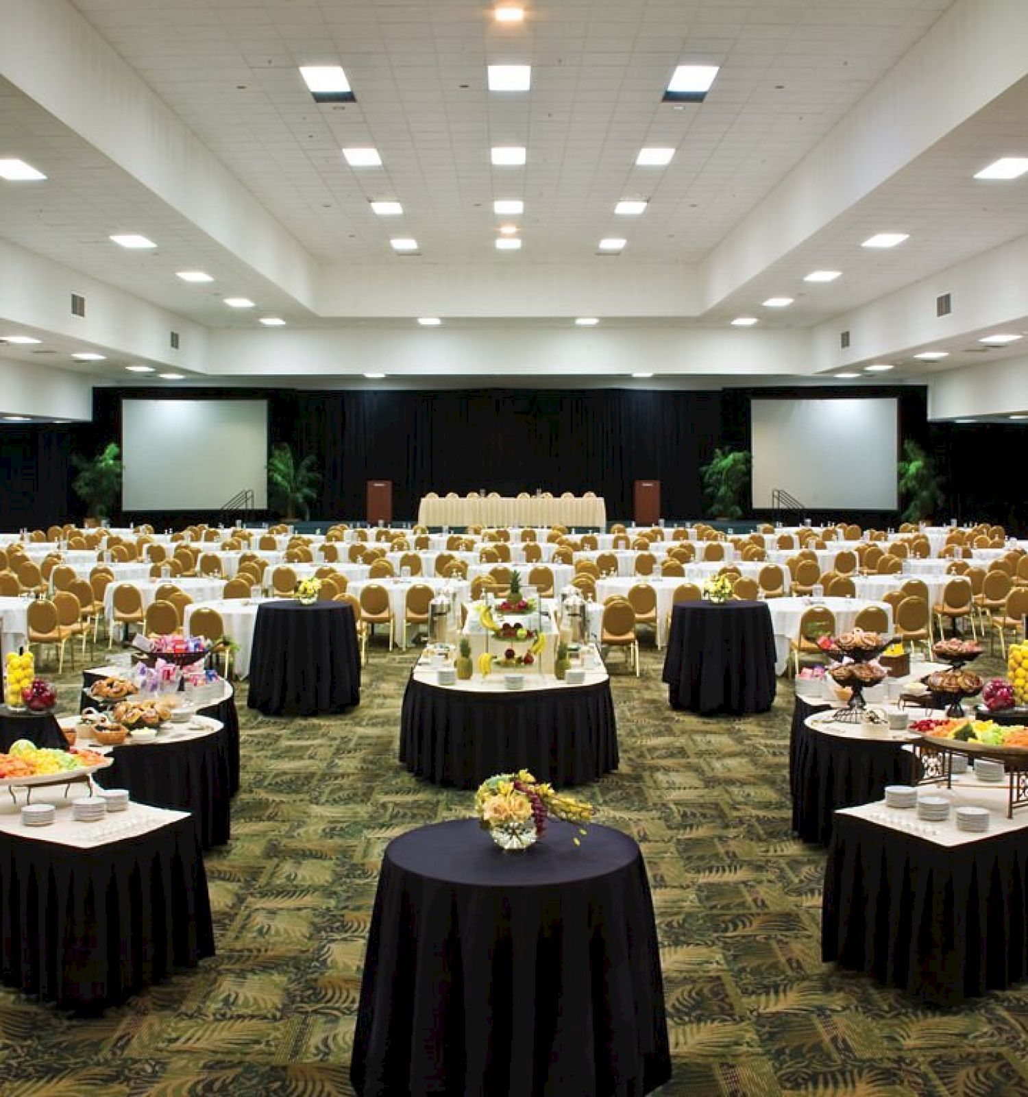 A banquet hall set up with round tables, chairs, and decorated centerpieces.