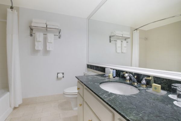 A clean bathroom with a sink, mirror, towels, and toilet.