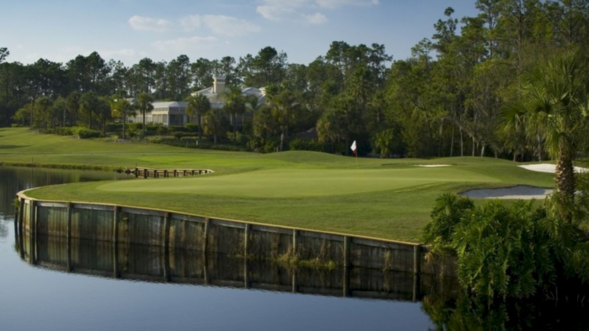 It's a scenic golf course with a green by the water, trees, and