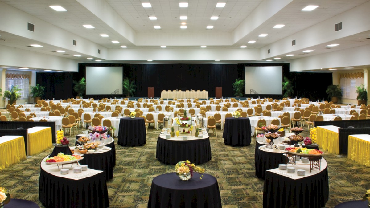 The image shows a large banquet hall set up for an event with round tables, chairs, and food stations, ending the sentence.