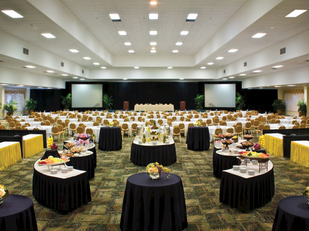The image shows a large banquet hall set up for an event with round tables, chairs, and food stations, ending the sentence.