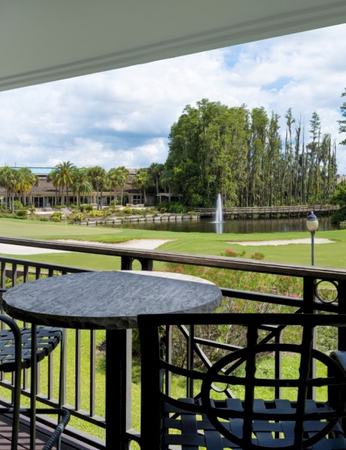 A balcony view with chairs overlooking a lush golf course.