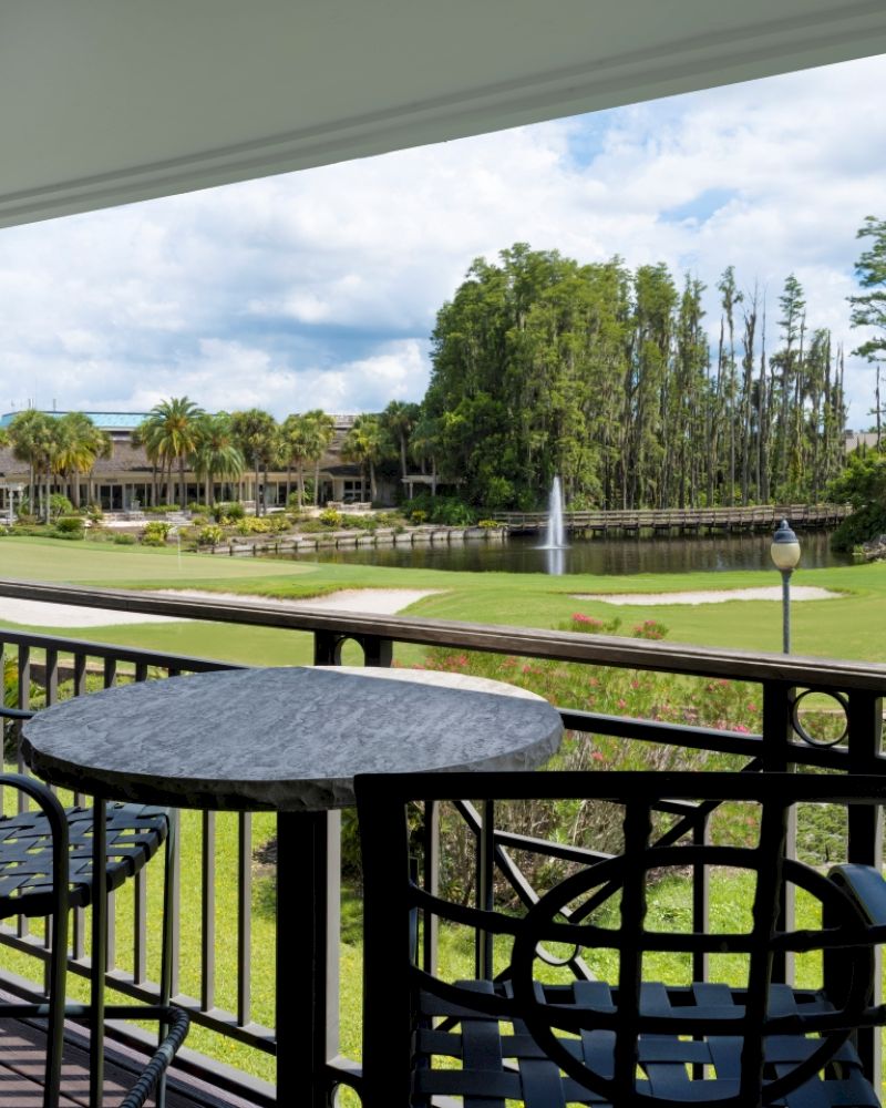 A serene balcony view with chairs, overlooking a golf course and landscaping.