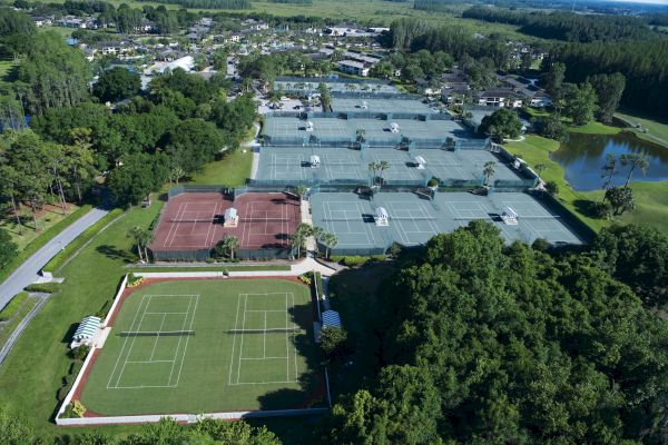 Aerial view of a sports complex with multiple tennis courts and a soccer field.