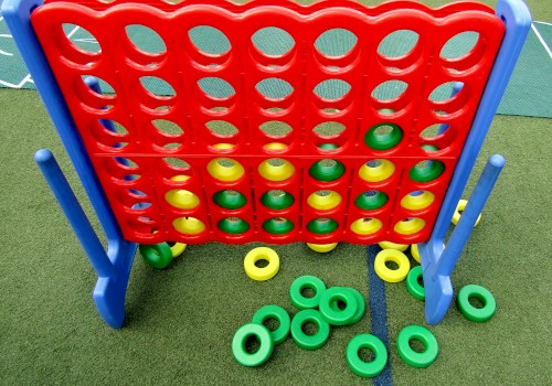 Large Connect Four game with red/yellow discs; some on the ground.