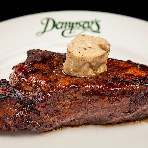 A grilled steak topped with a dollop of butter sits on a plate with the word “Donovan’s” written on the rim.