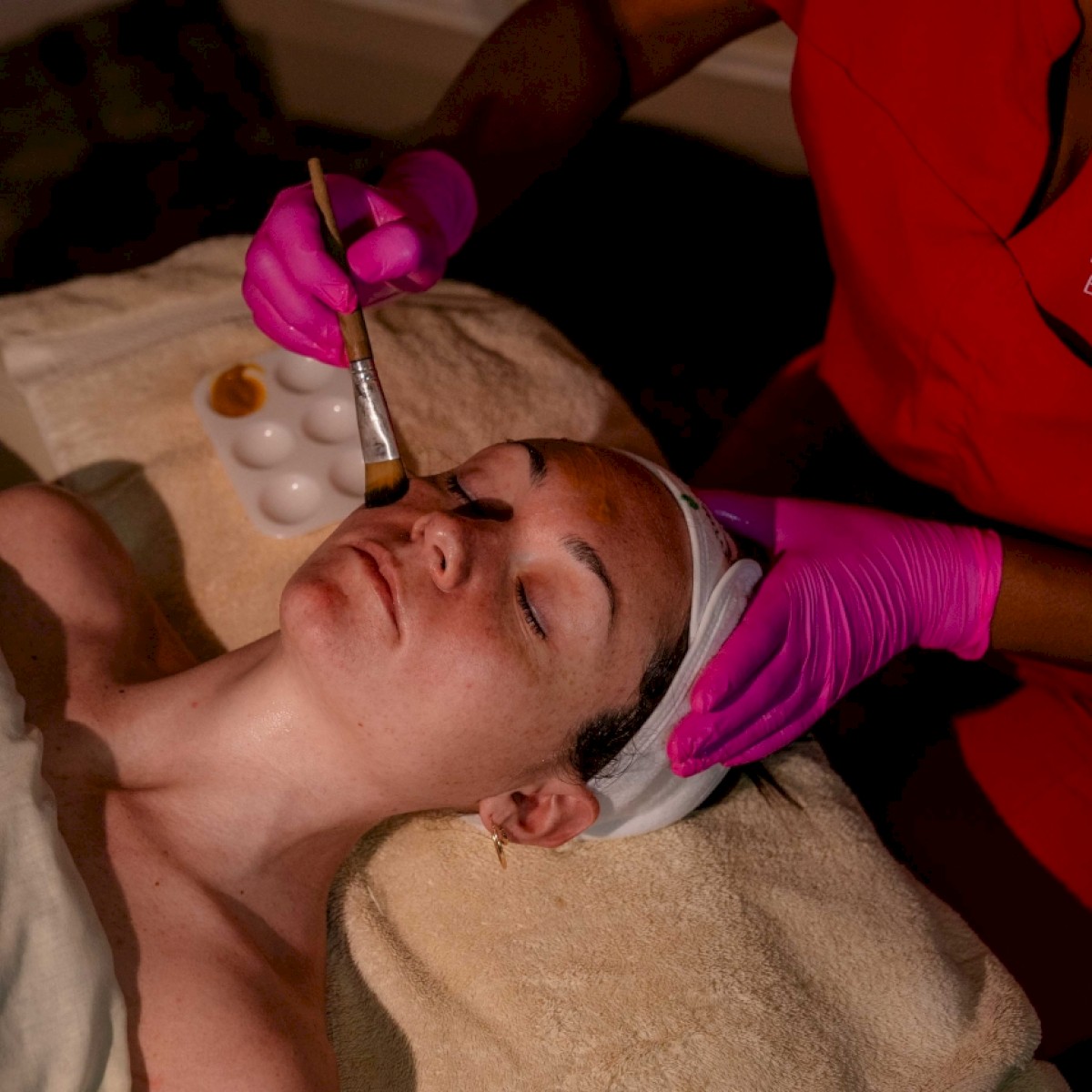 A person receives a facial treatment with a tool by a professional in gloves.