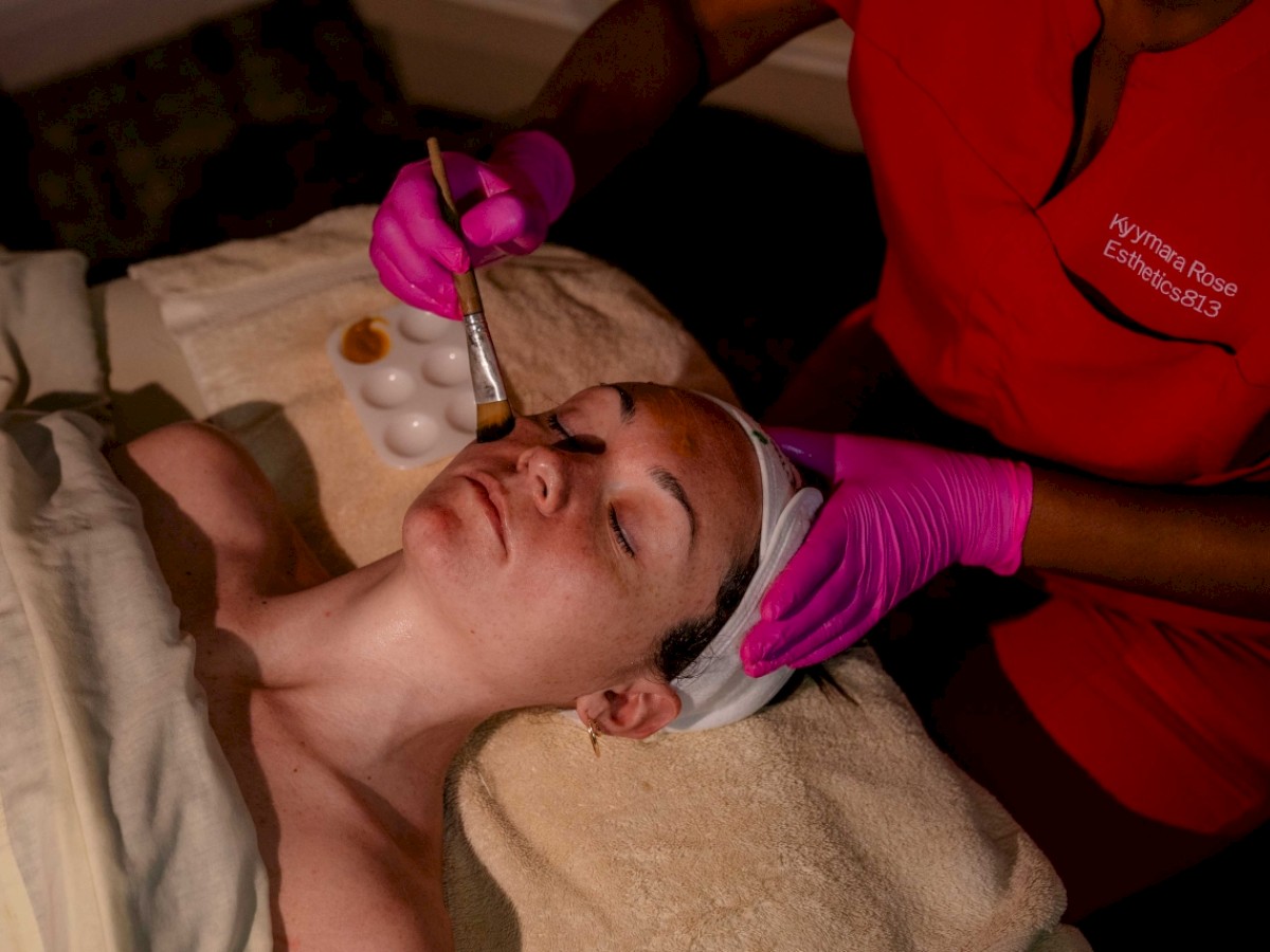 A person receives a facial treatment with a tool by a professional in gloves.