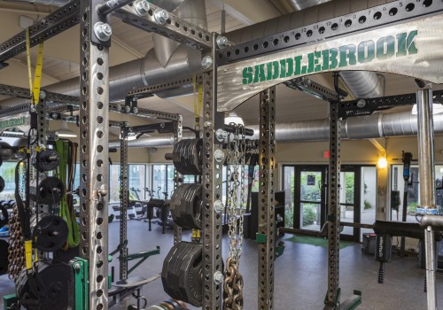 The image shows a well-equipped gym with various weightlifting and fitness equipment and the sign 