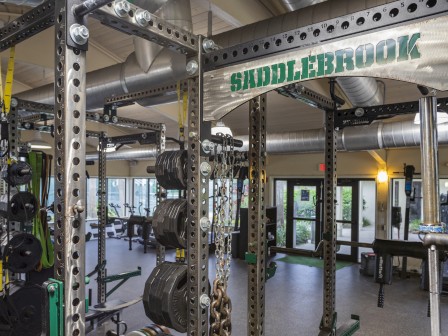 A gym interior with weight racks, machines, and various fitness equipment; the word 