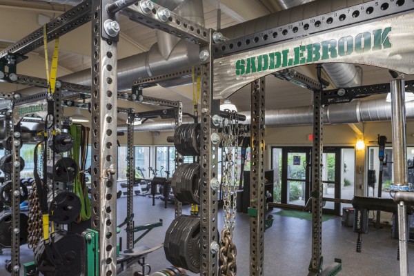 A gym interior with weight racks, machines, and various fitness equipment; the word 