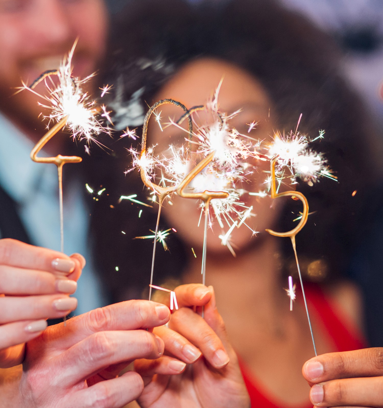 A group of people celebrating with sparklers shaped like the numbers 