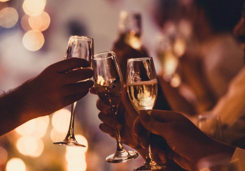 People are toasting with champagne glasses at a festive gathering, with warm lighting and blurred background creating a cozy ambiance.