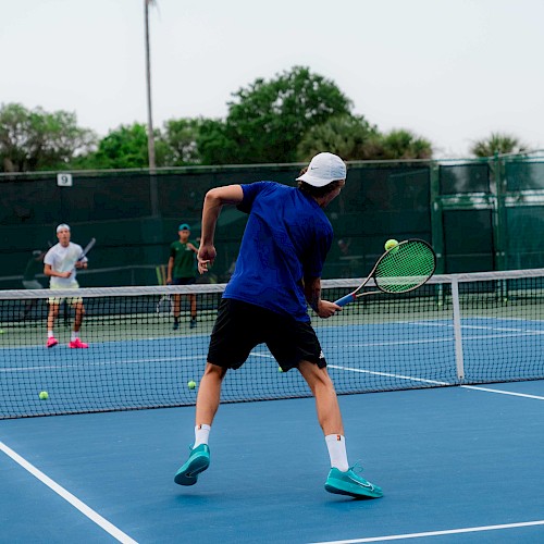 Two people are playing tennis on an outdoor court, with one player preparing to hit the ball.