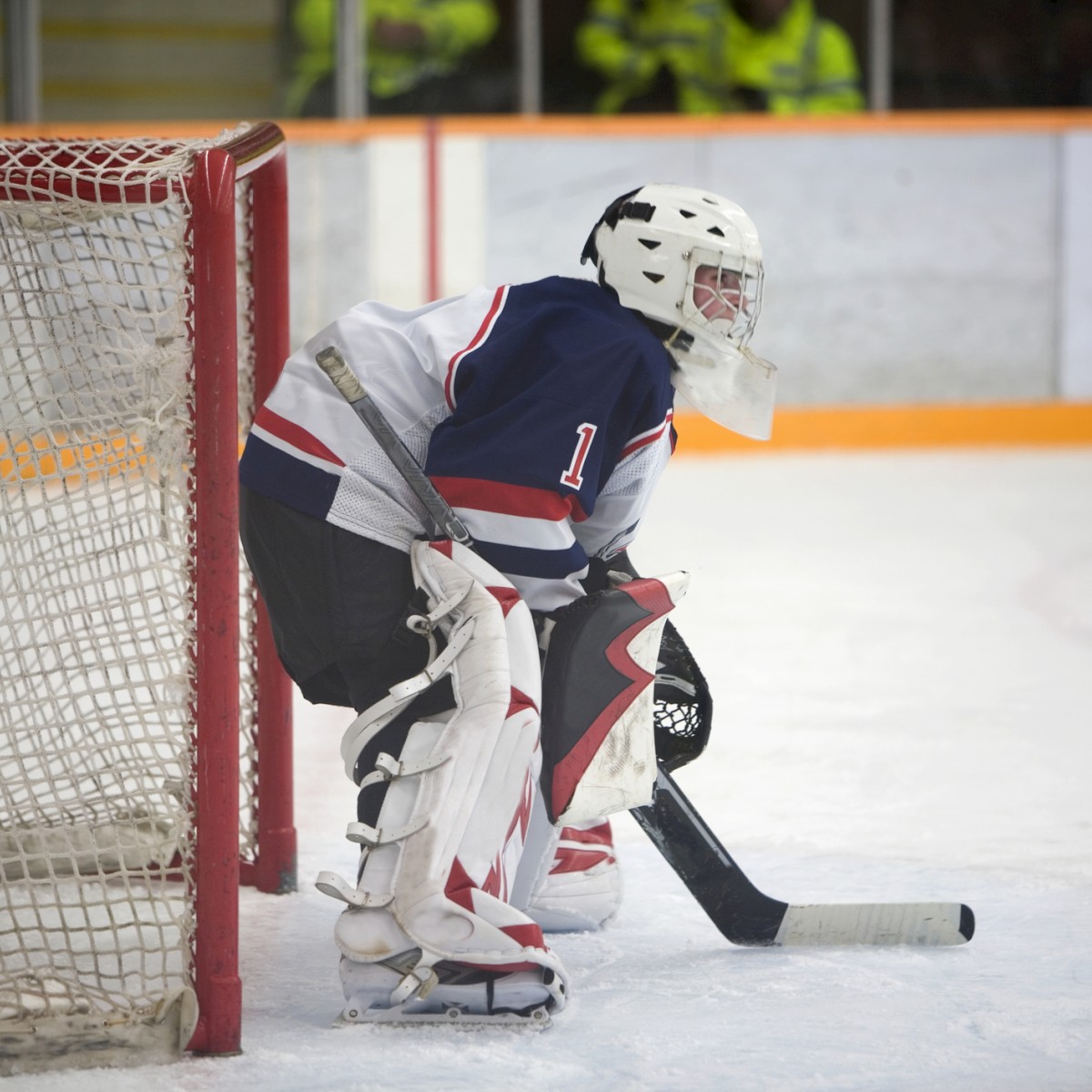 A hockey goalie in full gear is poised in front of the net during a game.