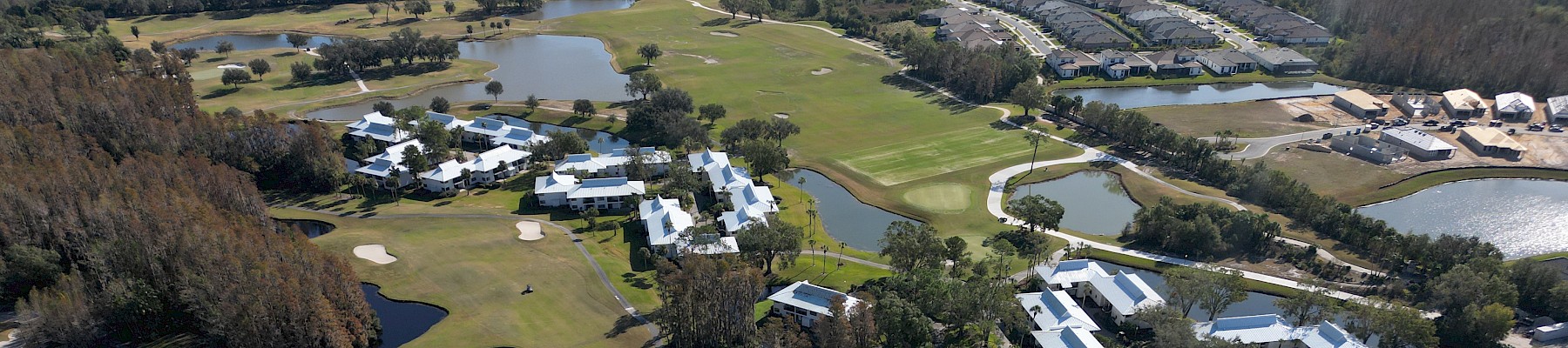 The image shows an aerial view of a resort with pools, green spaces, and multiple residential buildings.